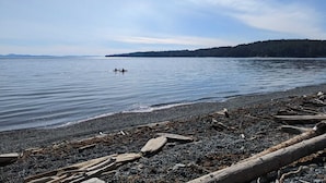 A calm lake with a rocky shoreline and a distant forested island. - Beautiful beachfront Villa on 80 acres of farmland! (Sooke)