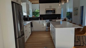 A modern kitchen with wooden beams, stainless steel appliances, and a central island. - Beautiful beachfront Villa on 80 acres of farmland! (Sooke)