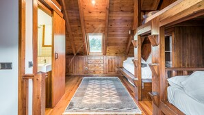 A wooden cabin bedroom with a bunk bed, a large rug, and a skylight. - Valartíes (Artíes)