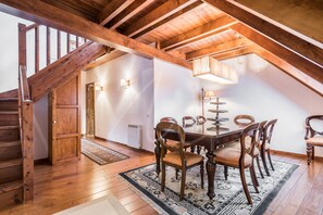 A dining area with a wooden table and chairs, a staircase, and a chandelier.