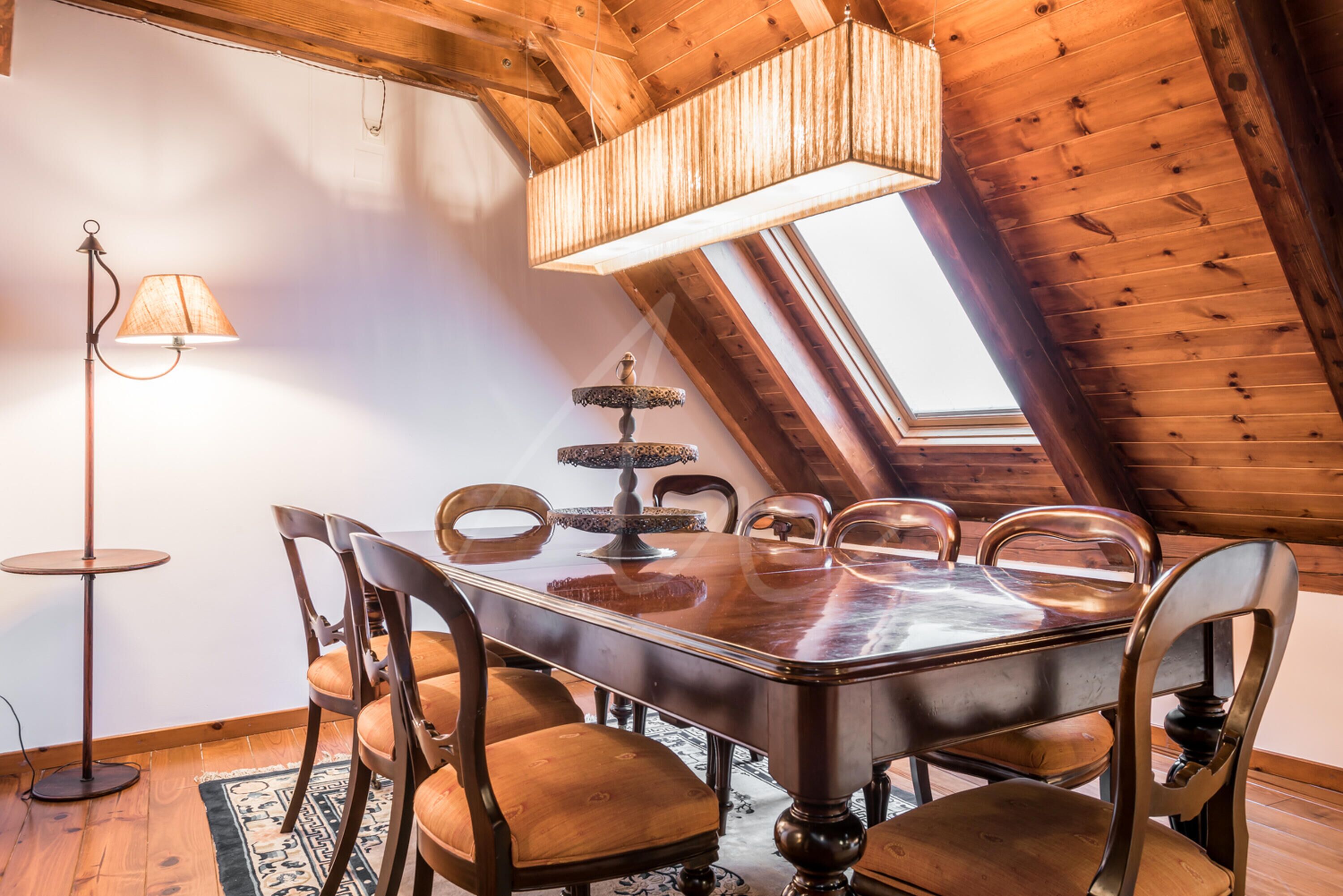 A dining area with a wooden table, six chairs, a floor lamp, and a chandelier.