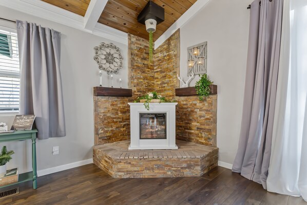 A fireplace with a stone surround, a decorative wall clock, and a small table with a plant.