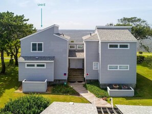 A two-story house with a central staircase, a covered porch, and a small garden area.