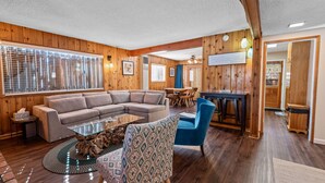 A cozy living room with a sectional sofa, a glass coffee table, and a patterned armchair.
