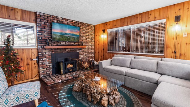 A cozy living room with a fireplace, a sofa, and a Christmas tree.