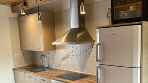 Eine moderne Küche mit Holzschränken, einer Edelstahl-Dunstabzugshaube, einem eingebauten Backofen und einem weißen Kühlschrank.