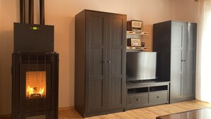 Ein Wohnzimmer mit Kamin, dunklen Holzschränken, einem Fernseher und einem Holztisch.