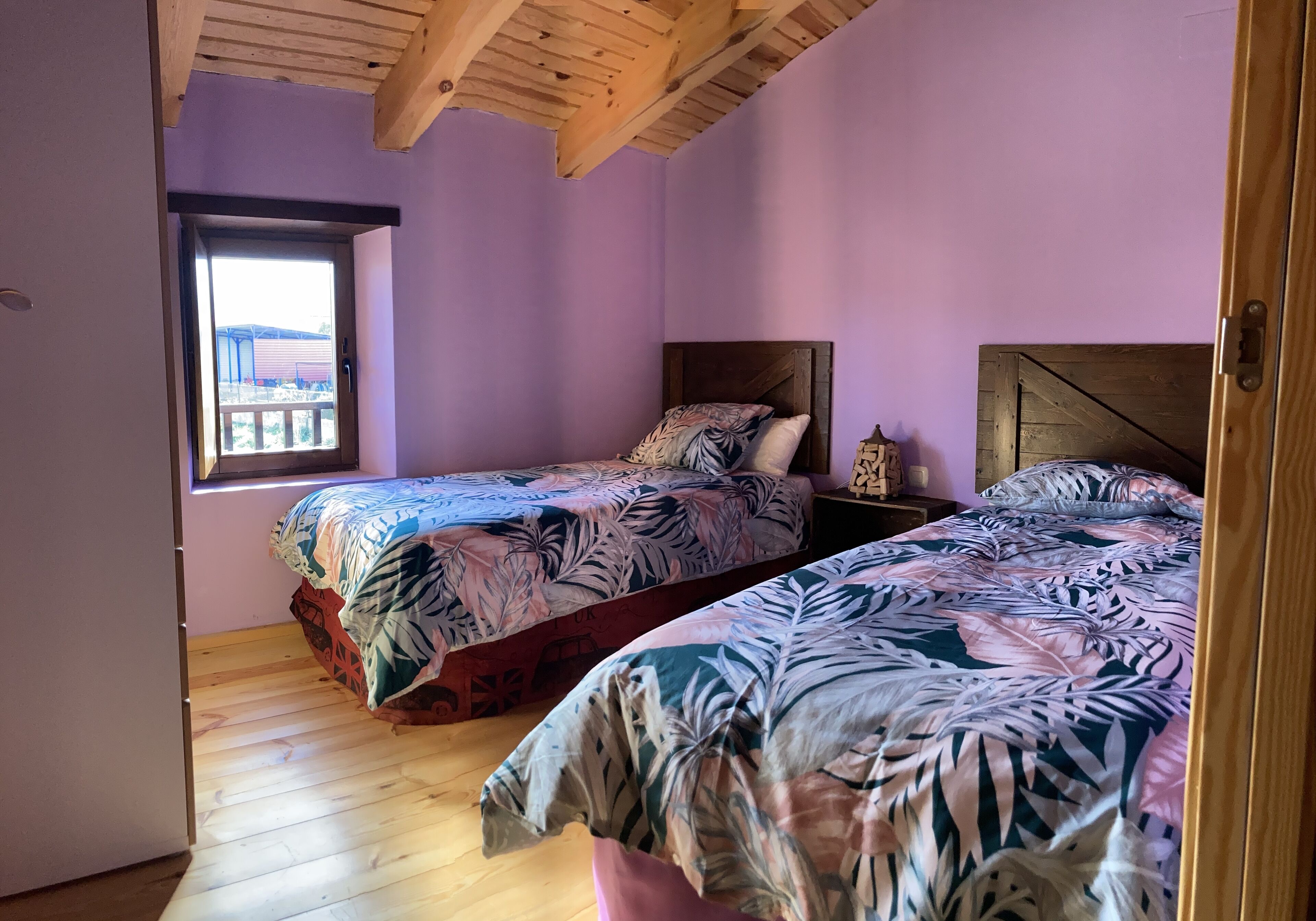 Un dormitorio con dos camas, suelo de madera y una ventana con vistas.