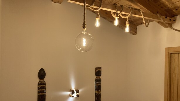 Eine Treppe mit Holzbalkon, einer Leuchte mit mehreren Lampen und zwei Wanddekorationen.
