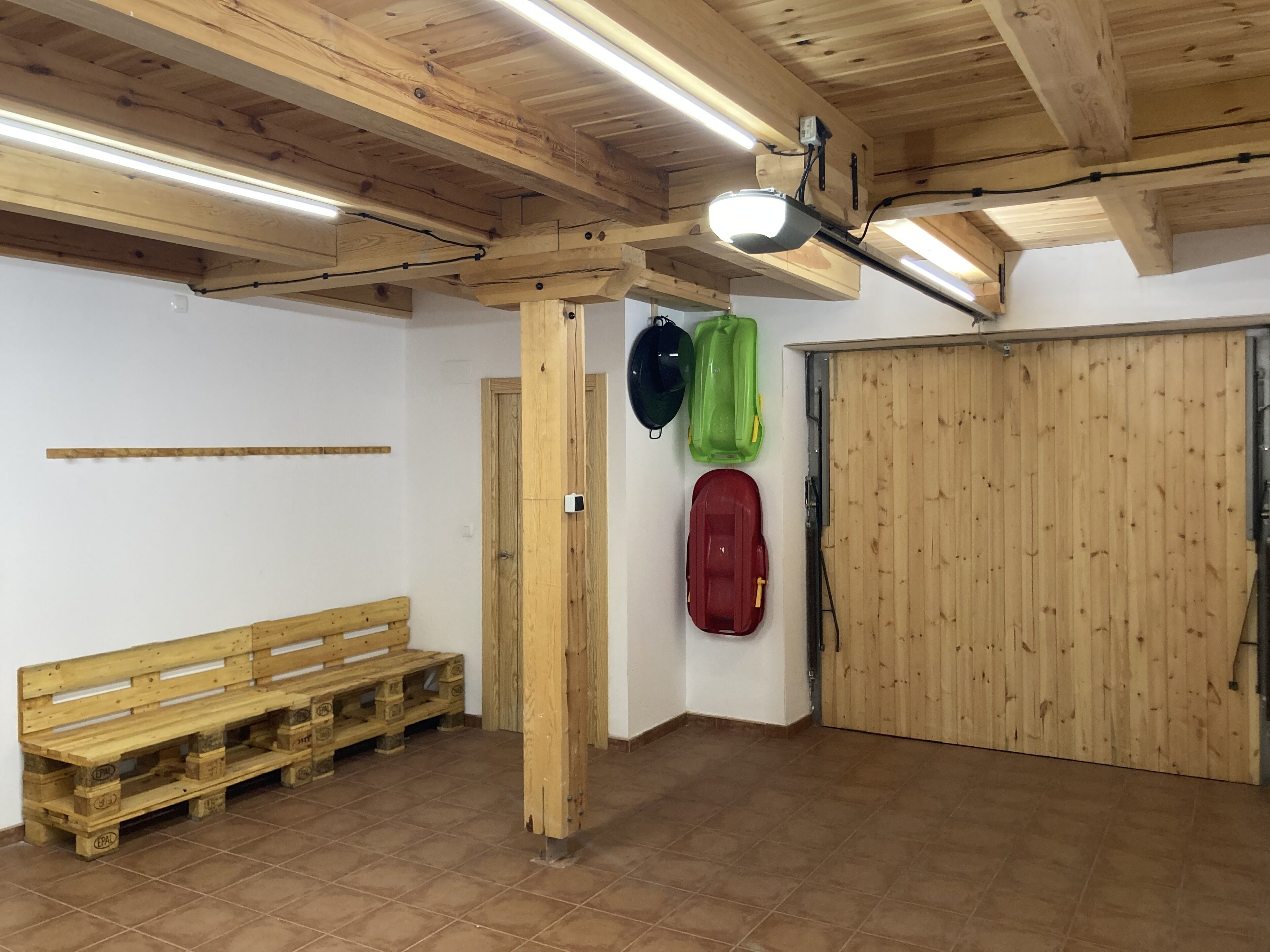 A room with a wooden bench, a door, and a wall-mounted projector.