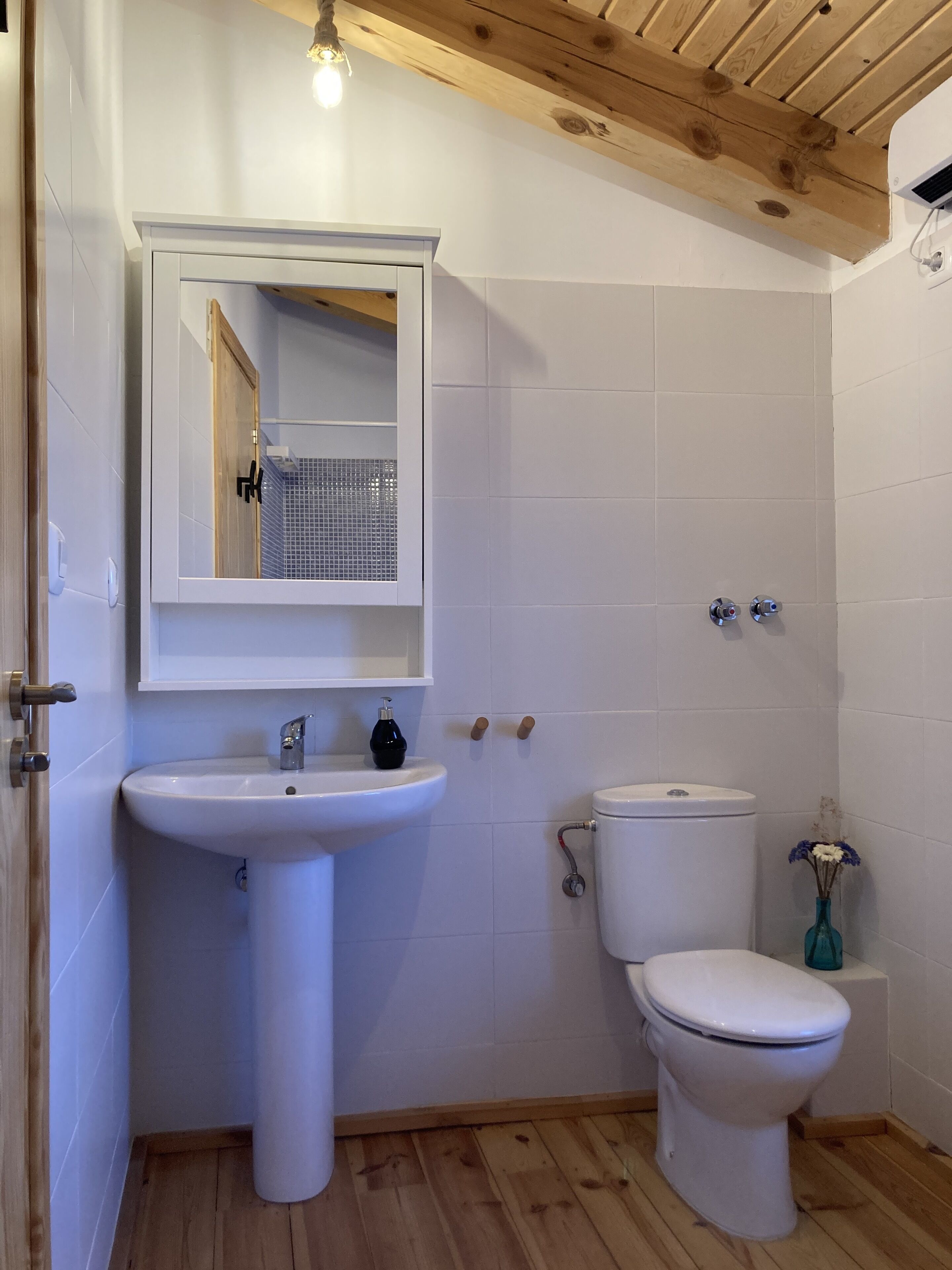 Un baño con un lavamanos blanco, un inodoro y un espejo sobre el lavamanos.