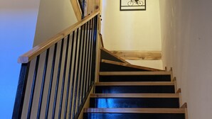 Eine Holztreppe mit schwarzen Geländern, die zu einer Zwischenebene führt.