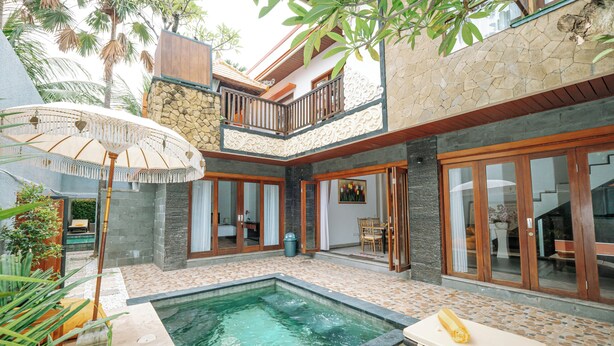 Una casa de dos pisos con piscina, balcón y zona de comedor.