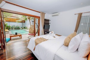 Camera d'albergo con un letto grande, pavimento in legno, vista piscina, televisore e ventilatore a soffitto.