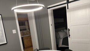 A dining area with a round table, black chairs, a pendant light, and a sliding door leading to a bedroom. - New Spacious single w/ parking.  Bikes, XBOX, (Phoenixville)