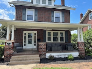 A two-story brick house with a porch, a front door, and a mailbox.