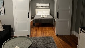 A bedroom with a bed, a bedside table, a chair, and a sliding door. - New Spacious single w/ parking.  Bikes, XBOX, (Phoenixville)