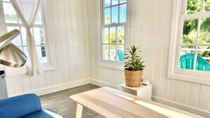 A room with a blue sofa, a wooden bench, and a small table with a woven basket. - Cottages on most stunning pink sand beach (North Palmetto Point)