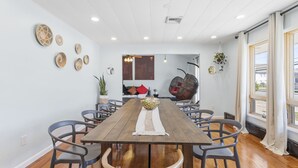 A dining area with a wooden table, grey chairs, and a woven placemat. - 5BD/3BA Ranch with Vaulted Ceilings in Heart of AC (Atlantic City)