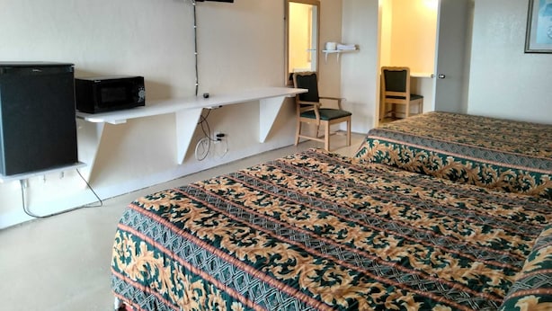 A hotel room with two beds, a TV mounted on the wall, a desk with a chair, and a small shelf. - Pharr Executive Inn good clean place for the price. near Airport, restaurants  (Pharr)