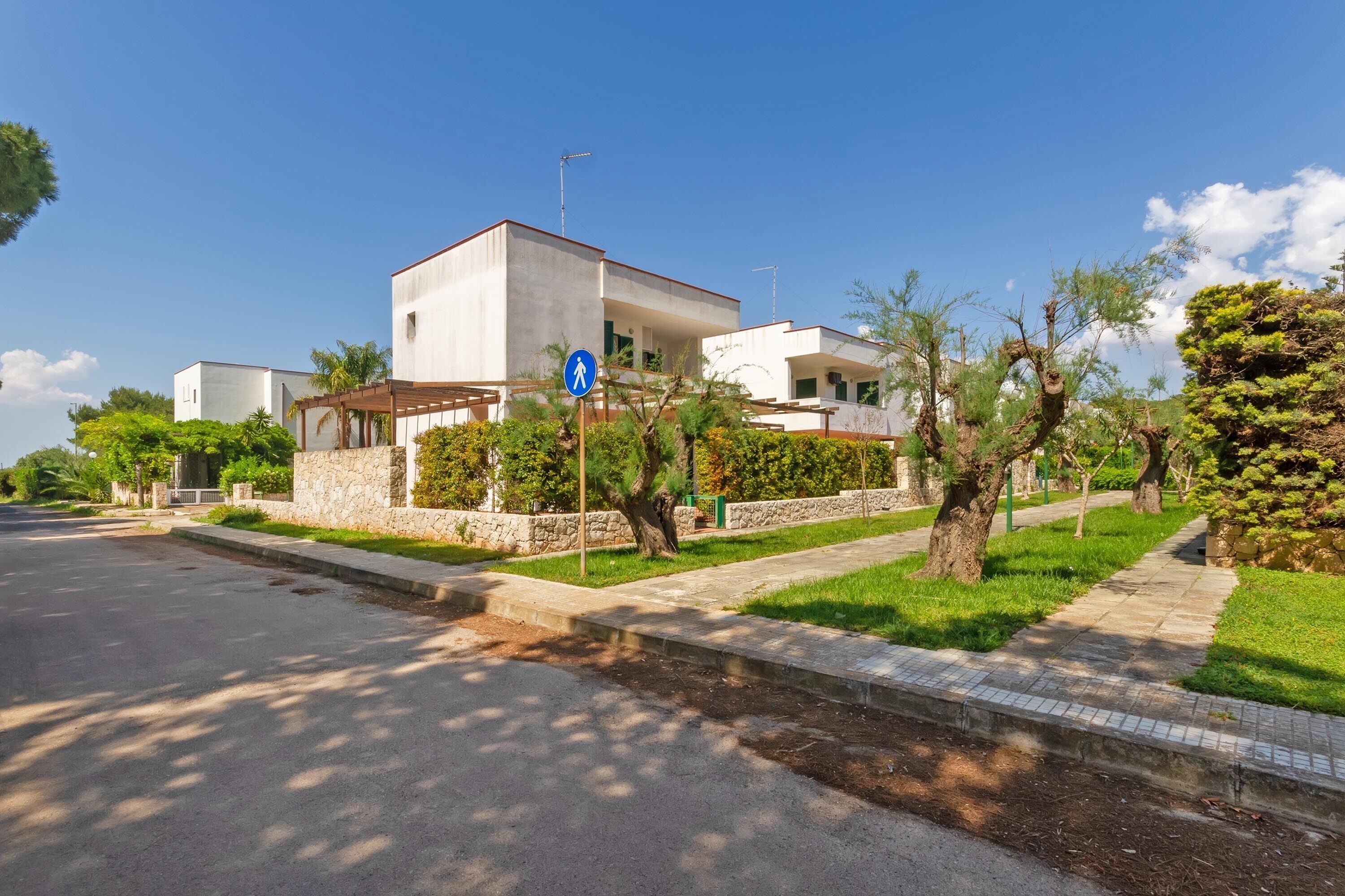 A modern two-story house with a stone facade, a visible garage, and a clear blue sky.