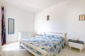 Une chambre à coucher comprenant un lit, une table de chevet, une commode, un miroir et un luminaire fixé au mur.
