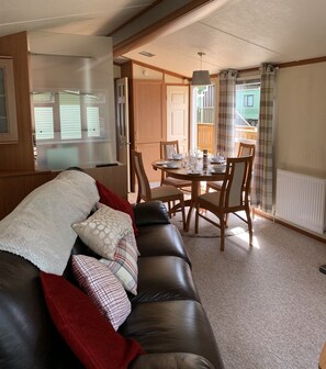 Relax in this inviting living room with a comfortable sofa, dining table for four, and exposed wooden beams.