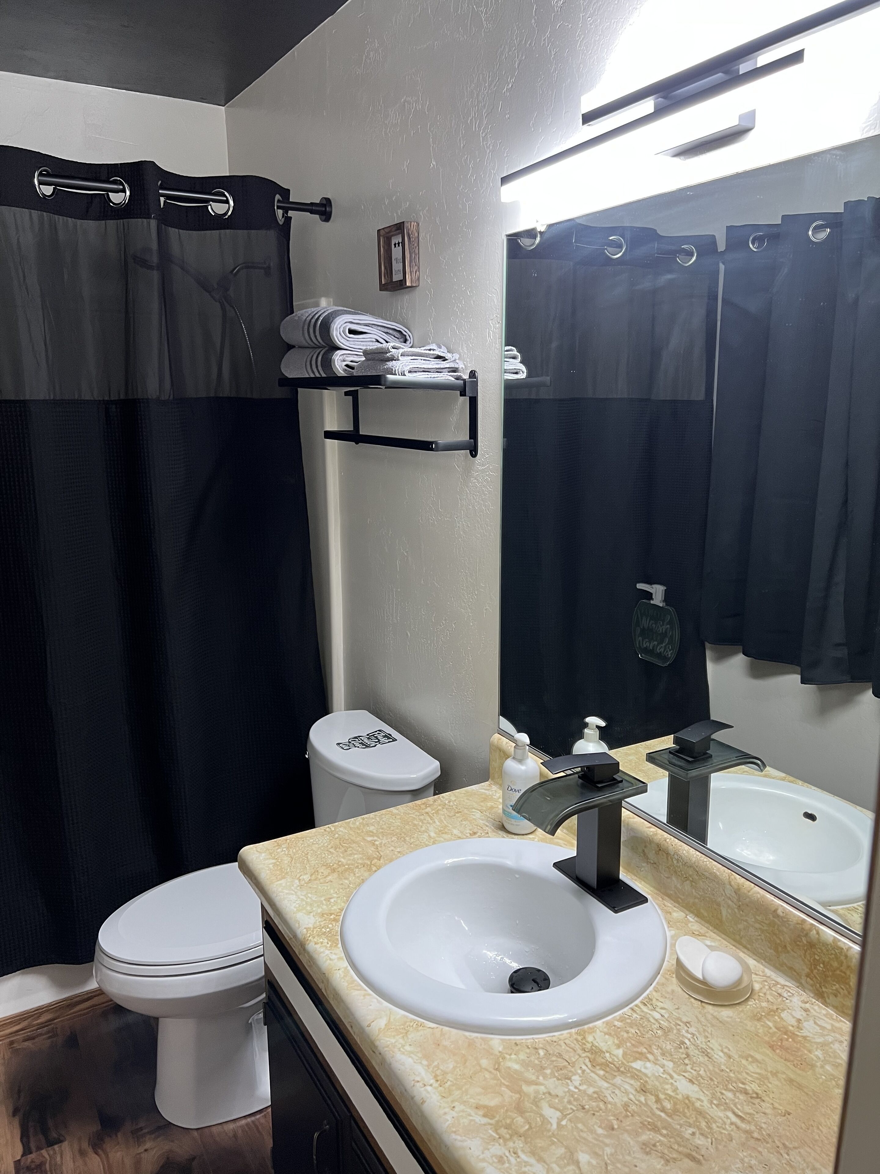 Een bad/douchecombinatie, een haardroger, handdoeken, zeep