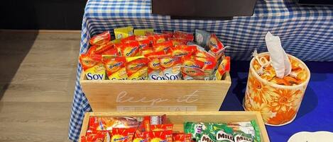 A buffet table with various food items, including packaged snacks and a cup with a napkin.