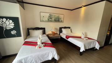 A hotel room with two beds, a nightstand, a lamp, and a painting on the wall.