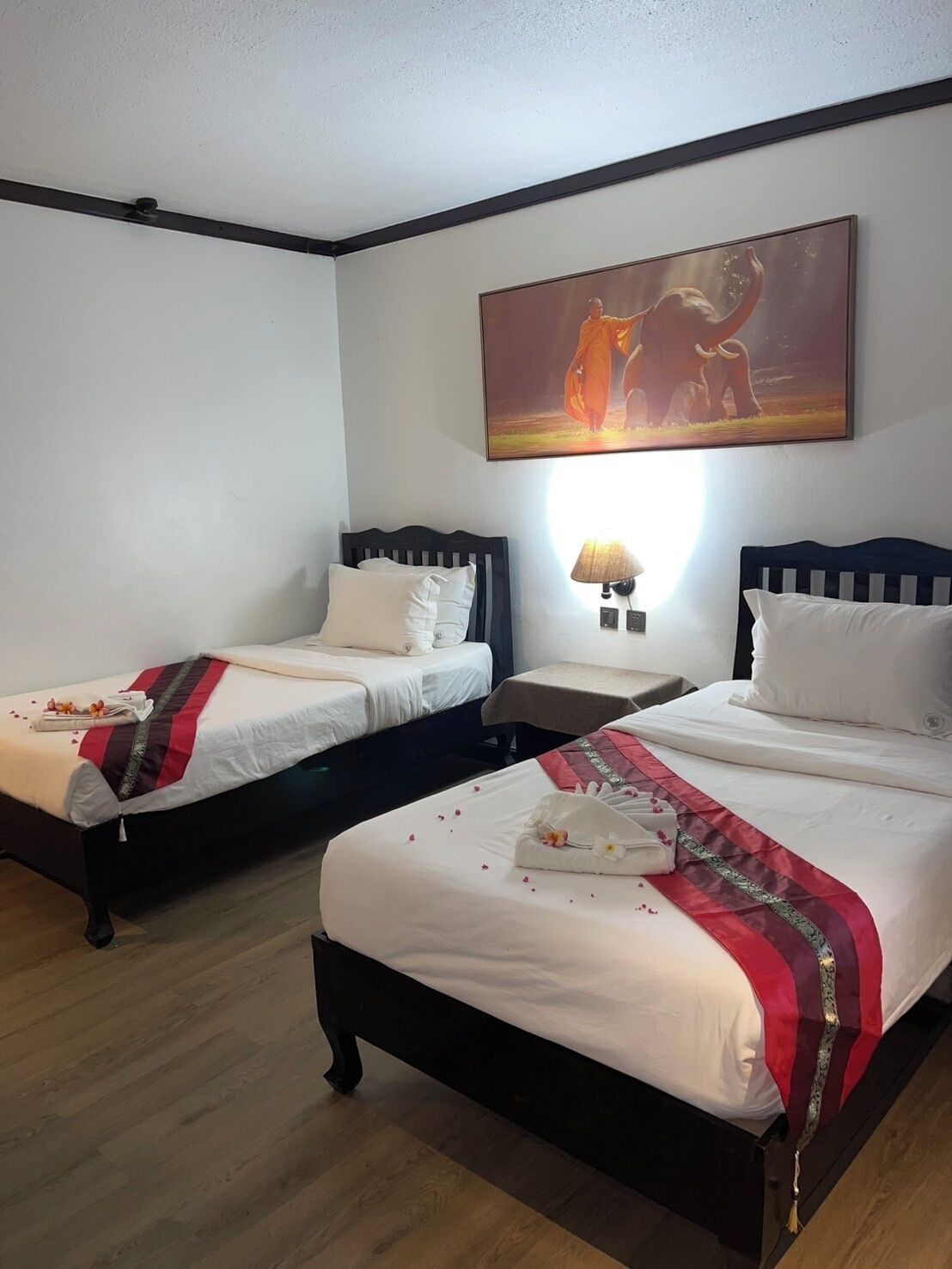 Habitación de hotel con dos camas, una mesita de noche, una lámpara y un cuadro en la pared.