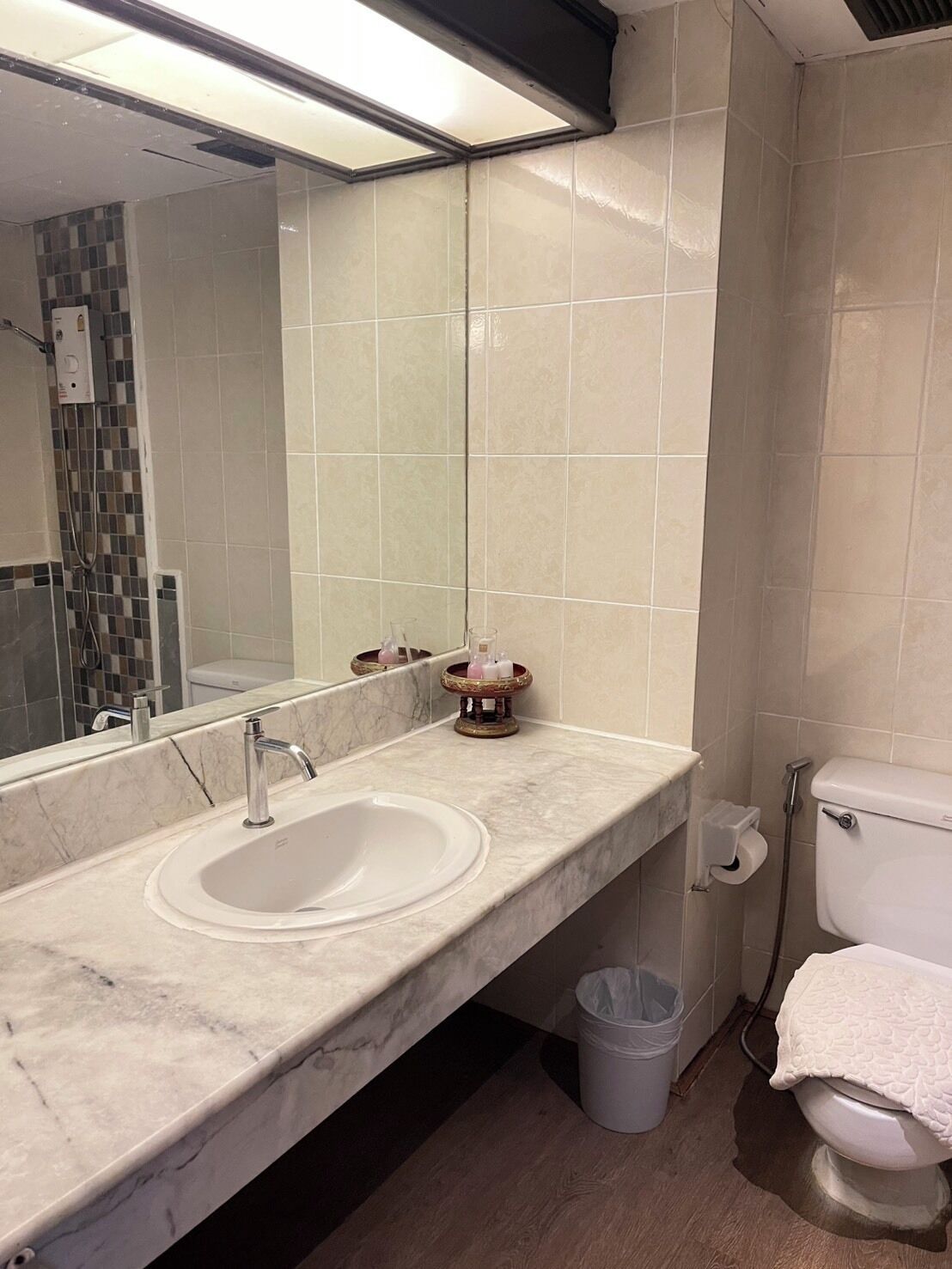A bathroom with a marble sink, a toilet, and a mirror.