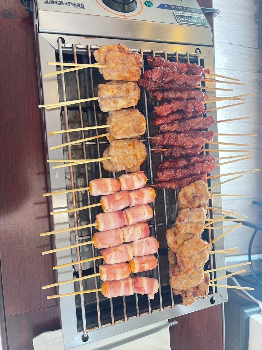 A grill with skewers of meat and bacon.