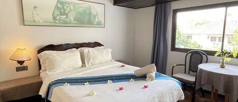 A hotel room with a bed, a bedside lamp, a window, and a wall-mounted air conditioner.