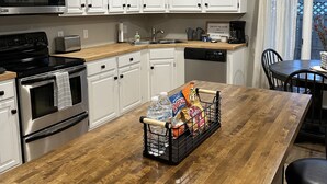 Een moderne keuken met witte kasten, roestvrijstalen apparatuur en een houten eiland met een mand vol lekkernijen.