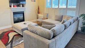 A living room with a fireplace, a sofa, a TV, and a window with blinds.
