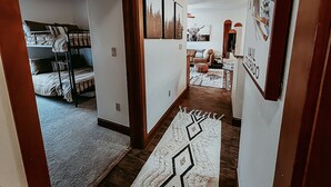 A hallway with a bunk bed, a sofa, and a rug.