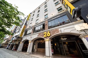 Um edifício com uma placa grande exibindo o número '26', com um café e um pub chamados 'Grey Fox' no andar térreo.