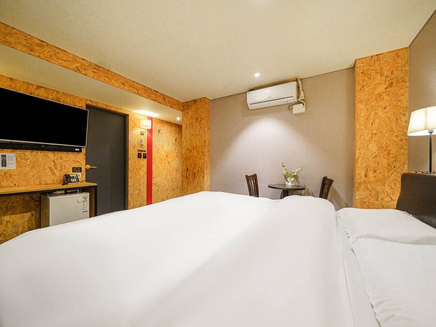 Habitación de hotel con una cama grande, un escritorio con televisión de pantalla plana, un refrigerador pequeño y una lámpara de escritorio.