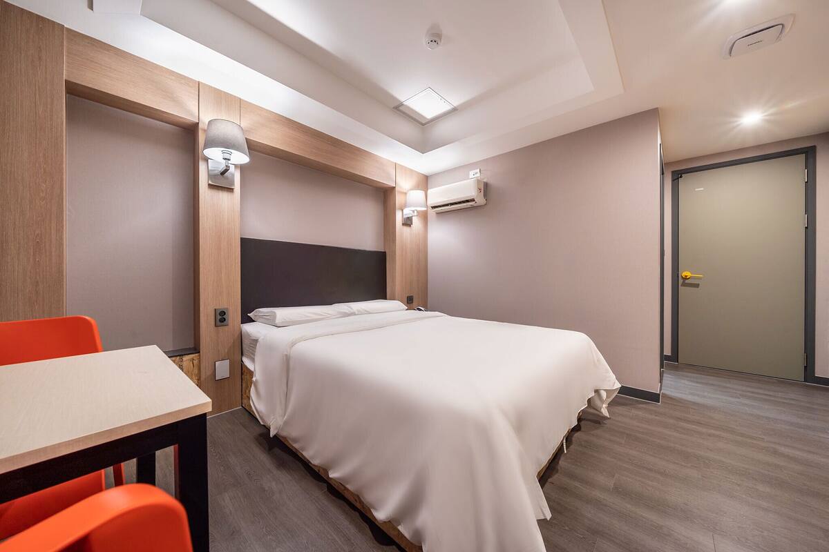 A hotel room with a bed, a desk, and chairs.