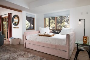 Une chambre à coucher avec un grand lit, un miroir et une fenêtre avec des stores.