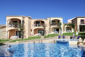 Un hôtel doté d’une piscine, de nombreux balcons avec des espaces extérieurs aménagés pour s’asseoir, et un ciel d’un bleu éclatant.