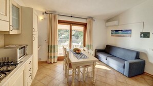 Eine kompakte Küche mit Esstisch, einer Couch und Blick ins Freie.