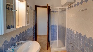 Ein Badezimmer mit Waschbecken, Spiegel, Dusche und gefliesten Wänden.
