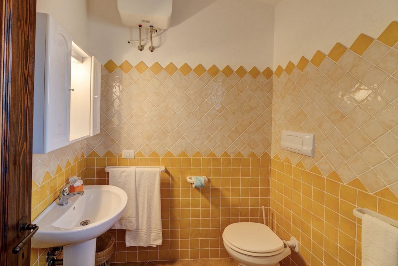 Une salle de bain équipée d’un lavabo, de toilettes et d’un porte-serviettes.