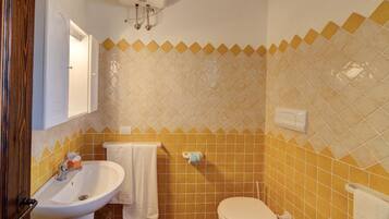 Une salle de bain équipée d’un lavabo, de toilettes et d’un porte-serviettes.