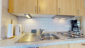 A modern kitchen with wooden cabinets, a stainless steel sink, a Bosch coffee maker, and a stove.