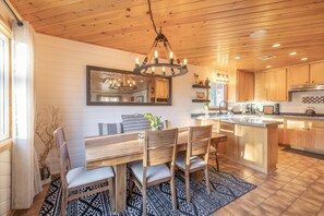 A modern kitchen with wooden cabinets, a central island, and a chandelier. - MODERN RUSTIC CABIN W/SPA, WALKING DISTANCE TO SKI RESORT, ZOO & GOLF COURSE (Big Bear Lake)