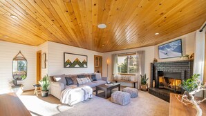 Un salon chaleureux avec un plafond en bois, une cheminée, un canapé et une table basse.