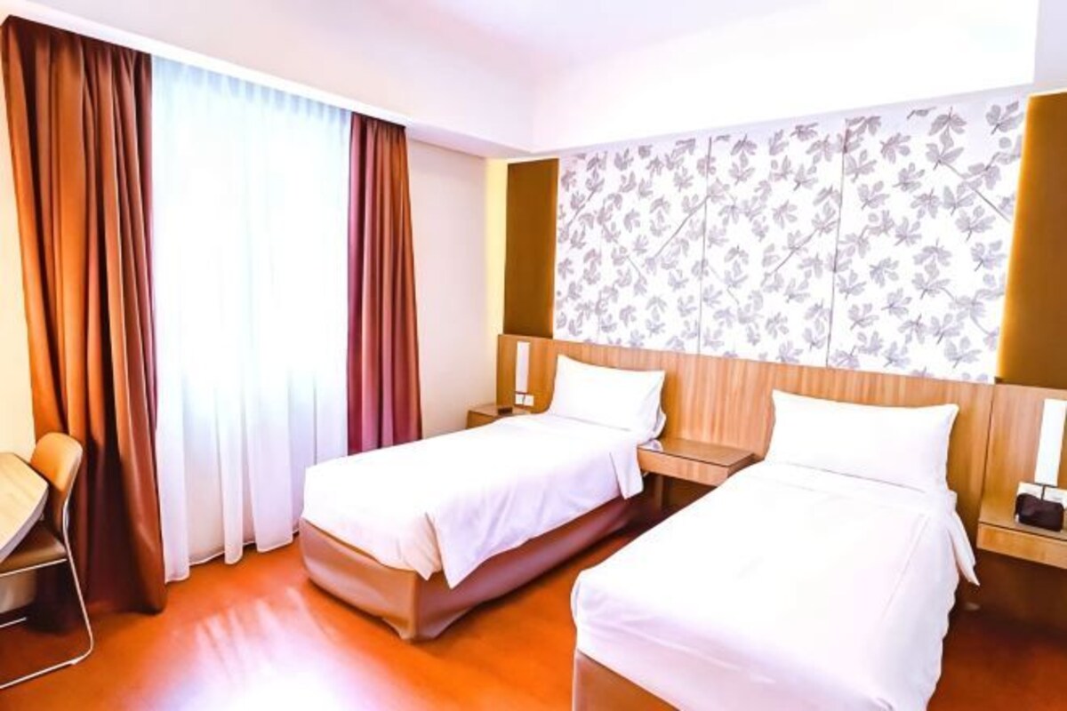 A hotel room with two beds, a desk, and a chair.